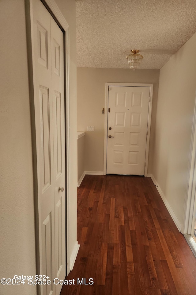 hall with dark hardwood / wood-style floors and a textured ceiling