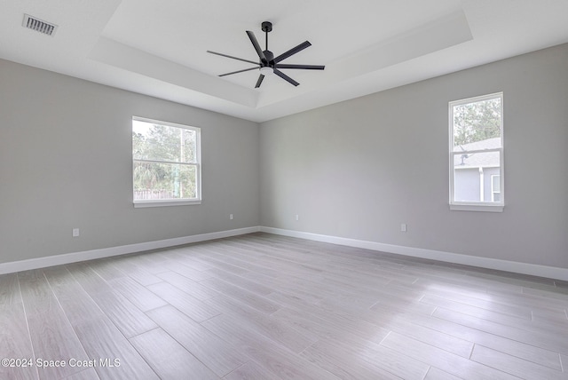 empty room with plenty of natural light and a tray ceiling