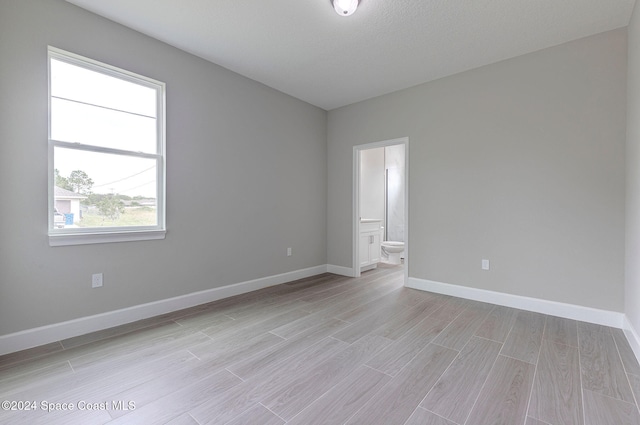 spare room with a textured ceiling and light hardwood / wood-style flooring