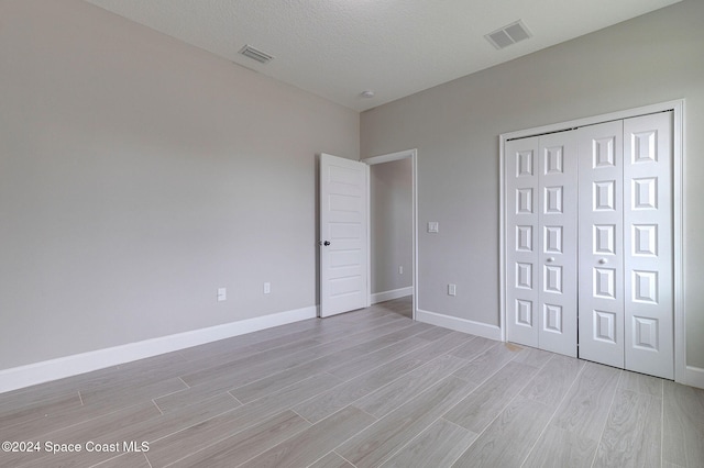 unfurnished bedroom featuring a textured ceiling and light wood-type flooring