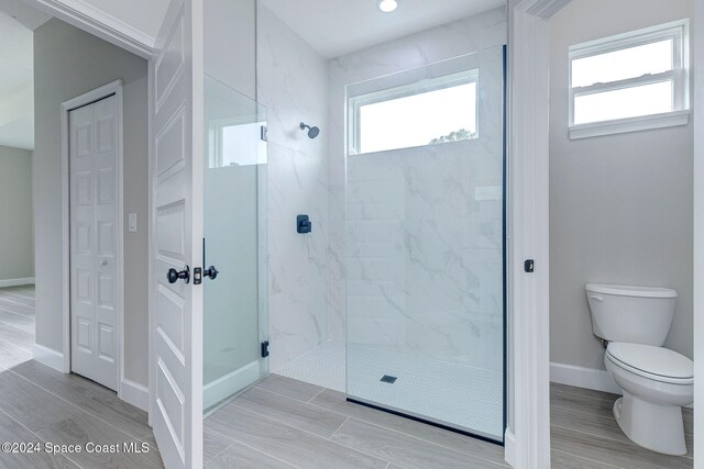 bathroom with tiled shower and toilet