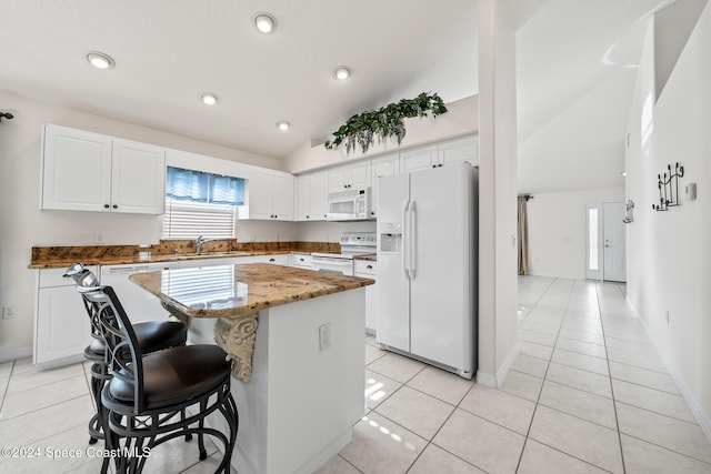 kitchen featuring white cabinets, light tile patterned floors, a kitchen island, and white appliances