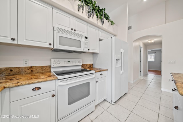 kitchen with light stone countertops, light tile patterned floors, white appliances, and white cabinetry