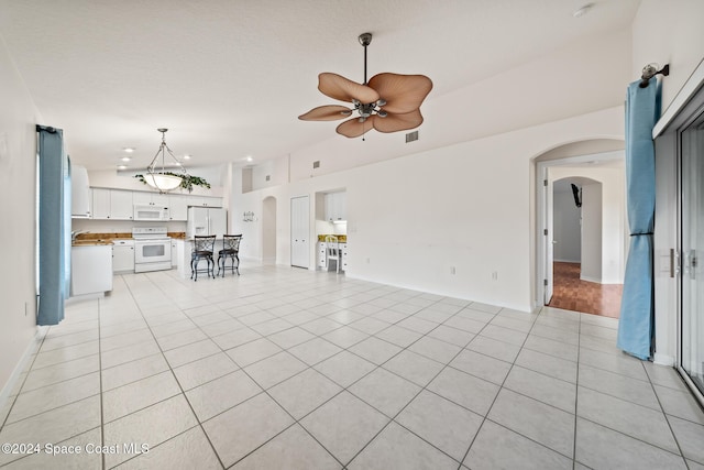 unfurnished living room with ceiling fan, sink, and light tile patterned floors