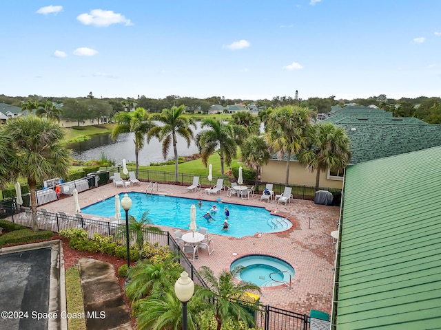 view of pool with a patio area, a water view, and a hot tub