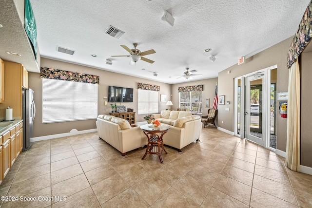 tiled living room featuring ceiling fan and a textured ceiling