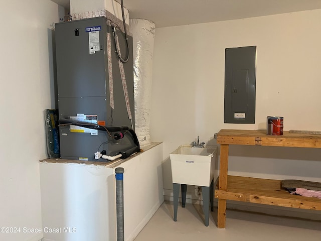 utility room with electric panel, heating unit, and sink