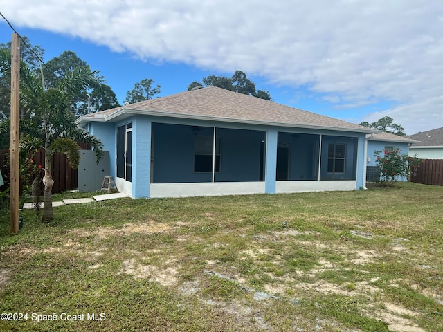 back of property with a yard and a sunroom