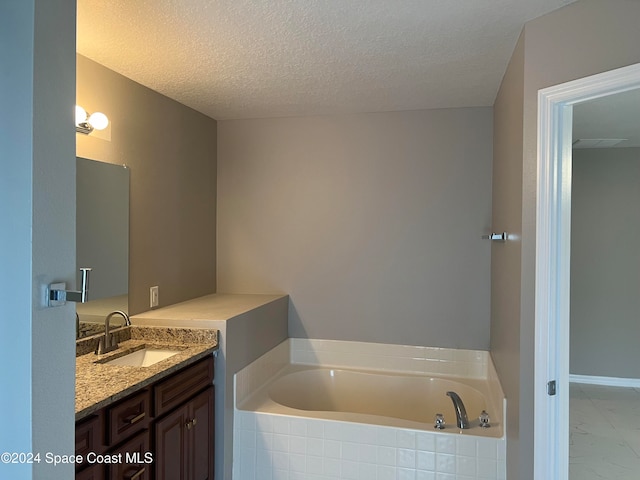 bathroom with vanity, a tub to relax in, and a textured ceiling