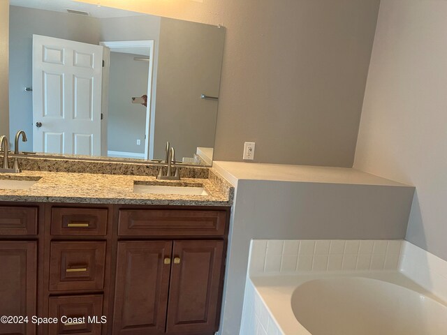 bathroom featuring vanity and a relaxing tiled tub