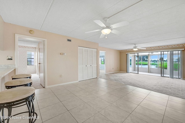 carpeted empty room with a textured ceiling, plenty of natural light, and ceiling fan