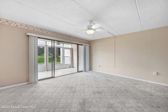 empty room with a textured ceiling, light colored carpet, and ceiling fan