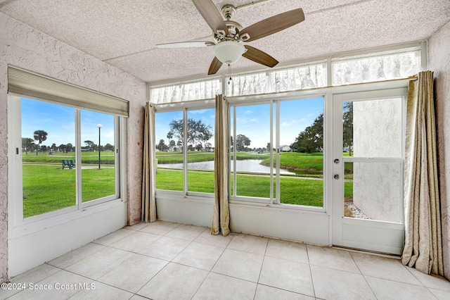 unfurnished sunroom with a wealth of natural light, ceiling fan, and a water view