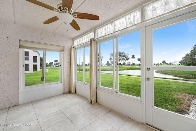 unfurnished sunroom featuring ceiling fan, a healthy amount of sunlight, and a water view