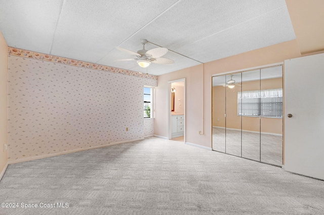 unfurnished bedroom featuring ceiling fan, a closet, light colored carpet, and a textured ceiling