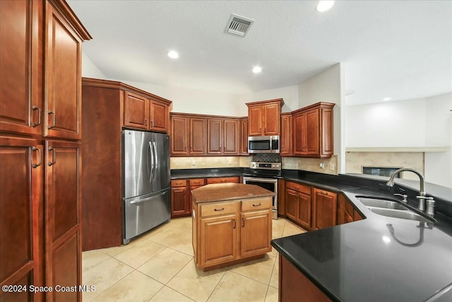 kitchen with backsplash, sink, light tile patterned floors, a kitchen island, and stainless steel appliances