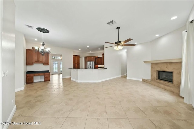 unfurnished living room with ceiling fan with notable chandelier, light tile patterned floors, and a fireplace