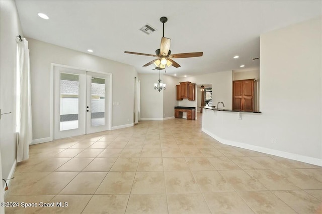 unfurnished living room with ceiling fan with notable chandelier, light tile patterned floors, and french doors