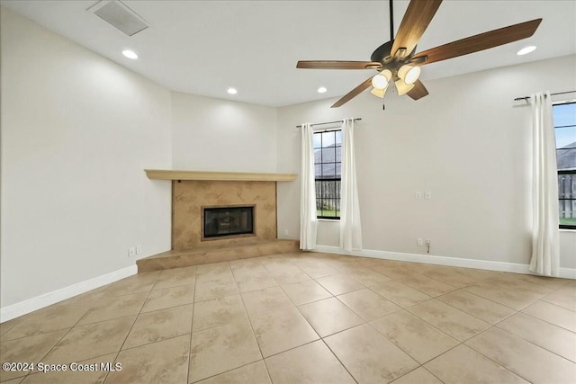 unfurnished living room with ceiling fan, a fireplace, and light tile patterned flooring