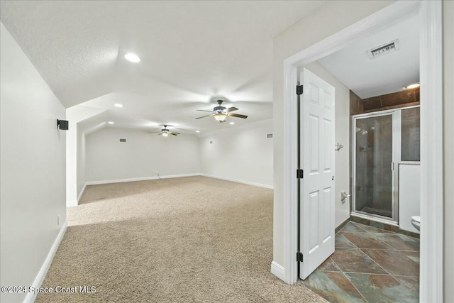 additional living space featuring dark colored carpet, ceiling fan, and vaulted ceiling