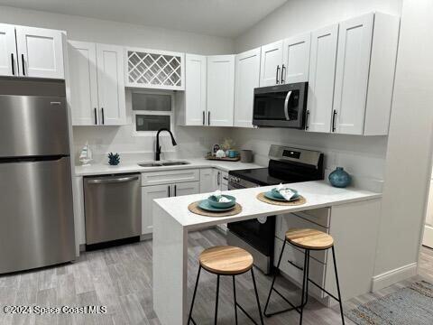 kitchen with white cabinets, a kitchen breakfast bar, sink, and appliances with stainless steel finishes