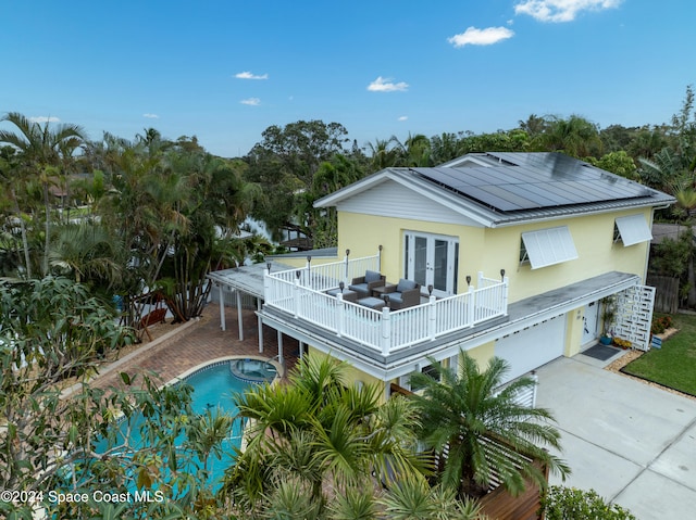 back of property with solar panels, a balcony, french doors, and a garage