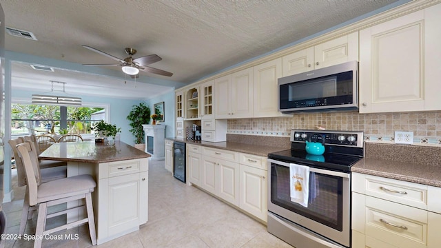 491 Indian Creek Dr, Cocoa Beach, FL 32931 - kitchen featuring stainless steel appliances, wine cooler, dark countertops, a breakfast bar area, and a ceiling fan