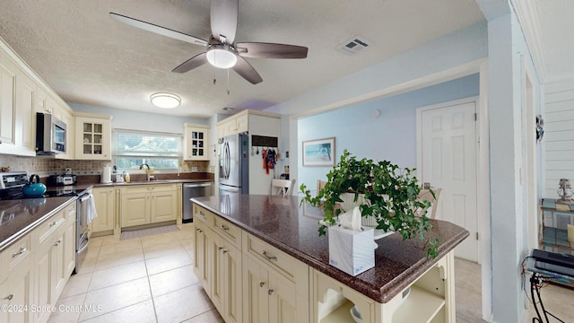 491 Indian Creek Dr, Cocoa Beach, FL 32931 - kitchen featuring appliances with stainless steel finishes, cream cabinets, a sink, tasteful backsplash, and open shelves