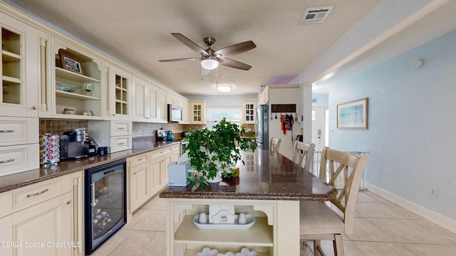 491 Indian Creek Dr, Cocoa Beach, FL 32931 - kitchen with beverage cooler, appliances with stainless steel finishes, light tile patterned floors, tasteful backsplash, and a ceiling fan