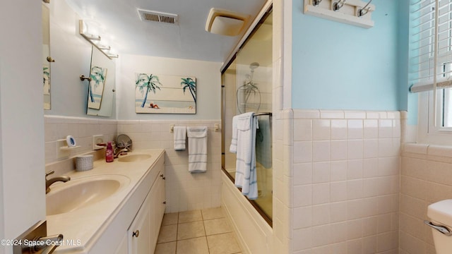 491 Indian Creek Dr, Cocoa Beach, FL 32931 - bathroom with tile walls, tile patterned floors, wainscoting, bath / shower combo with glass door, and double vanity