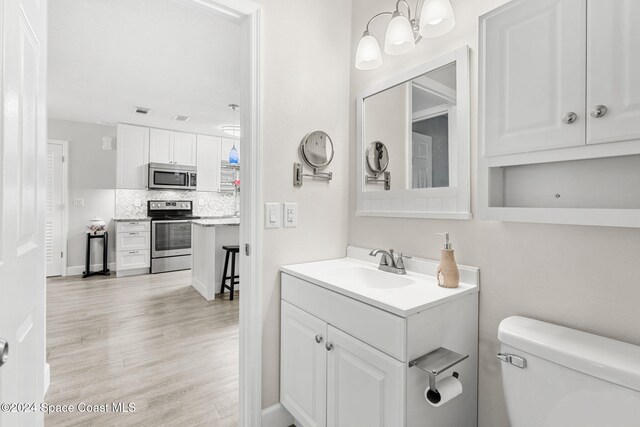 bathroom featuring vanity, hardwood / wood-style flooring, toilet, and tasteful backsplash