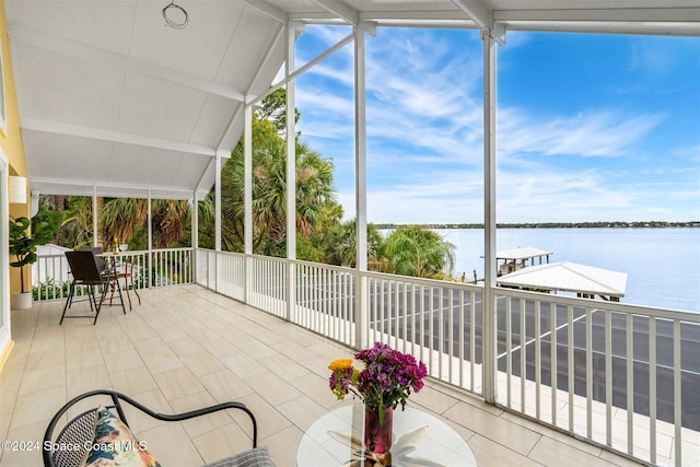 sunroom featuring a water view and lofted ceiling