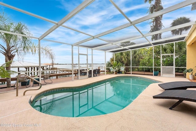 view of swimming pool with a water view, glass enclosure, and a patio area