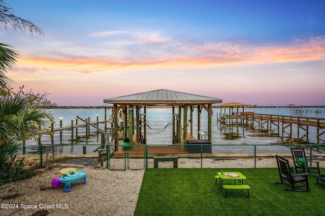 view of dock with a water view and a yard