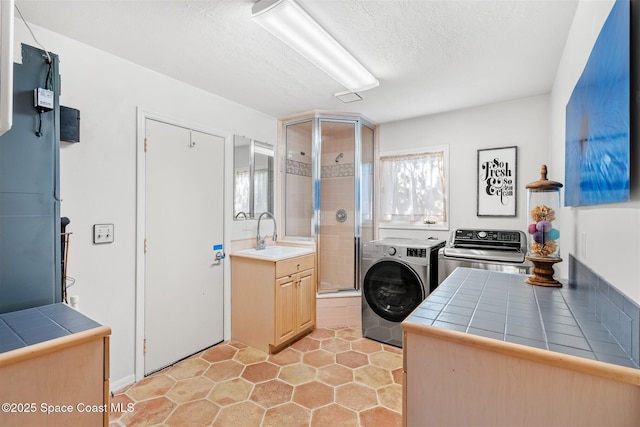 clothes washing area featuring a wealth of natural light, sink, a textured ceiling, and independent washer and dryer