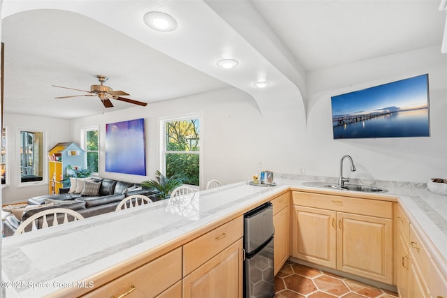 kitchen with ceiling fan, sink, light brown cabinets, tile countertops, and light tile patterned floors