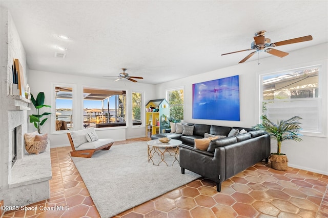 living room with ceiling fan and a large fireplace