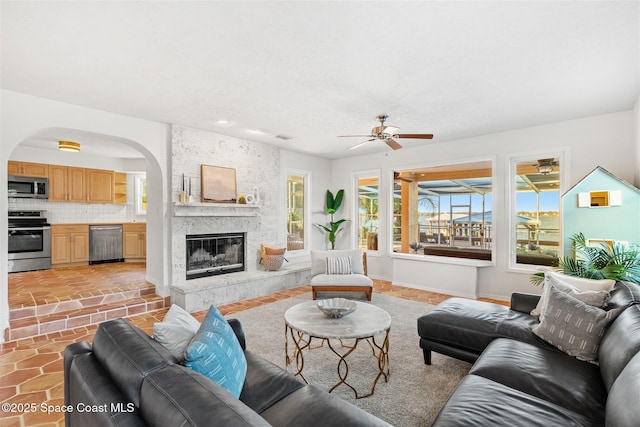 living room with a fireplace and ceiling fan