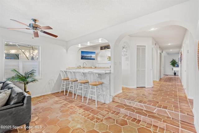 kitchen featuring a kitchen breakfast bar, ceiling fan, and sink