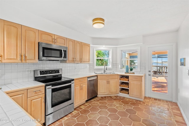 kitchen featuring tile counters, light brown cabinets, sink, and appliances with stainless steel finishes