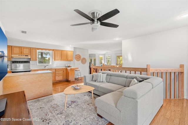 living room featuring ceiling fan, light wood-type flooring, and sink