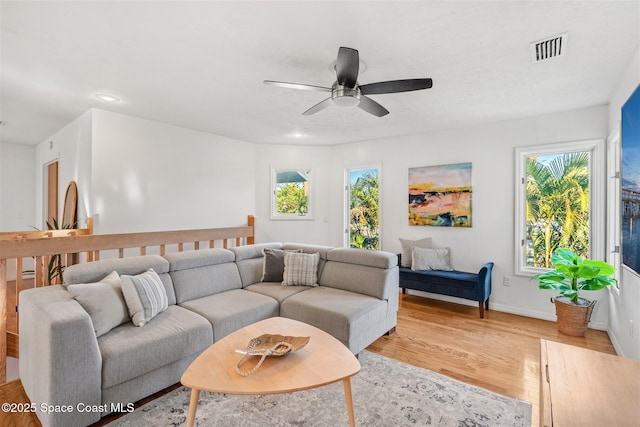 living room with ceiling fan, light wood-type flooring, and a wealth of natural light