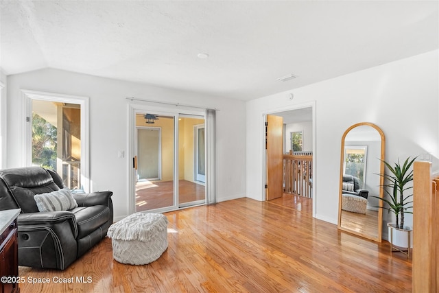 living room featuring a healthy amount of sunlight, light wood-type flooring, and lofted ceiling