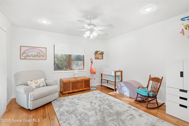 living area with hardwood / wood-style floors and ceiling fan