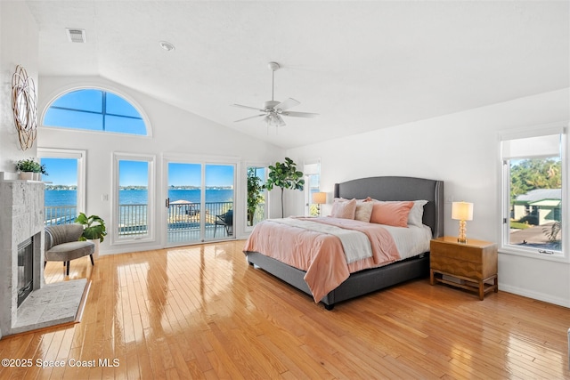 bedroom with access to exterior, light wood-type flooring, and a water view