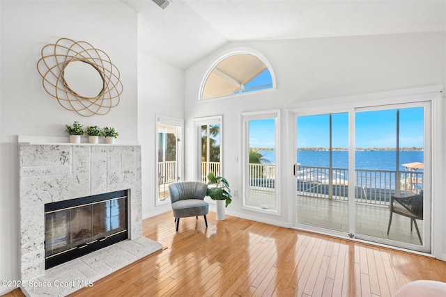 living area with a water view, a healthy amount of sunlight, and hardwood / wood-style flooring