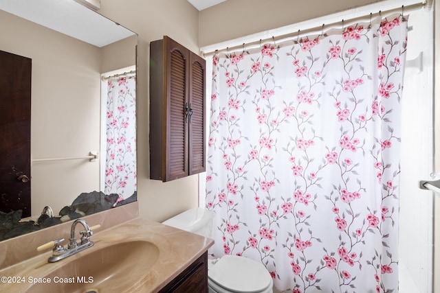 bathroom with curtained shower, vanity, and toilet