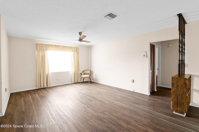 unfurnished room featuring ceiling fan, dark wood-type flooring, and a textured ceiling