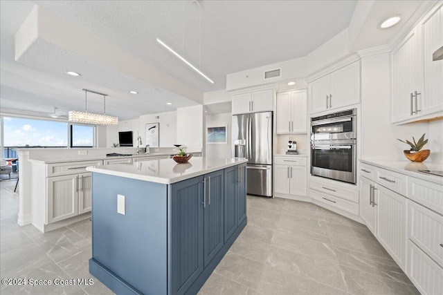 kitchen with white cabinets, a textured ceiling, a center island, and stainless steel appliances