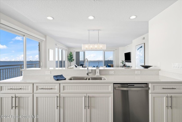 kitchen with sink, stainless steel dishwasher, pendant lighting, a textured ceiling, and a water view